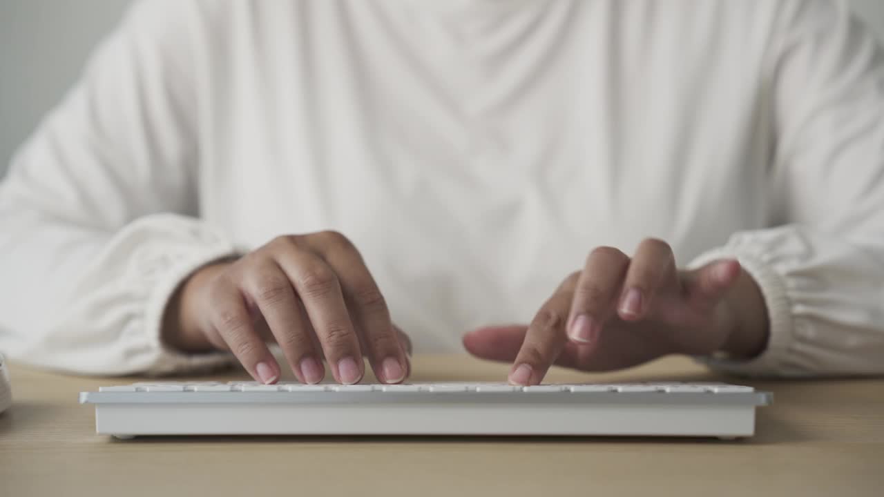 亚洲妇女在家里用电脑键盘打字的双手视频下载