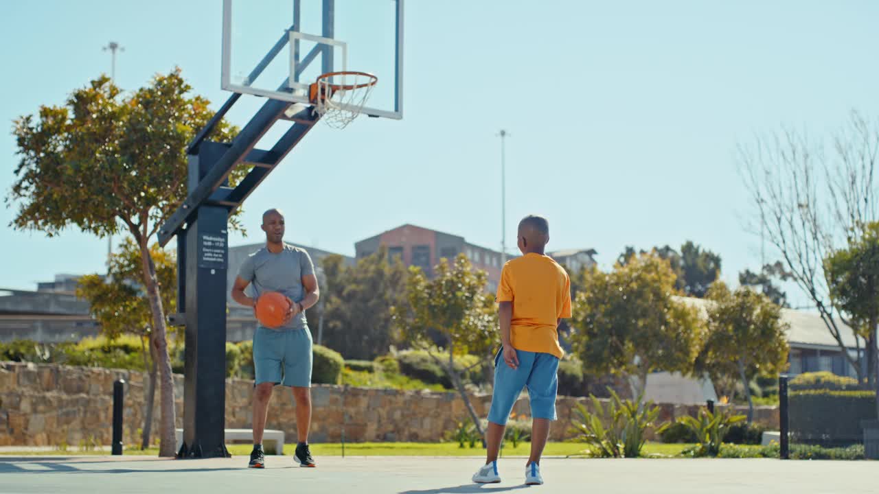 篮球，父亲和孩子，在公园里运动，一起玩耍，通过运动和锻炼建立联系。黑人男子和孩子在室外篮球场一起打球，投篮。视频下载