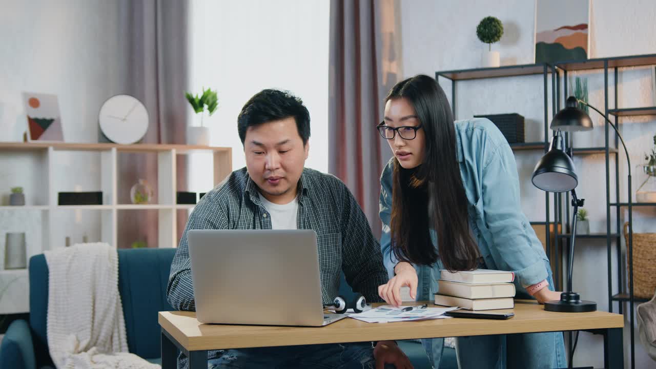 长相好看、积极自信的30岁中国自由职业者在电脑上修改共同项目时互相帮助，然后击掌视频下载