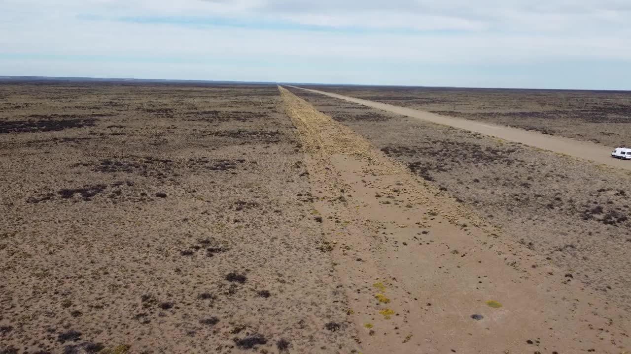航拍视频后视图的小型白色面包车行驶在砾石路平坦干旱景观视频下载