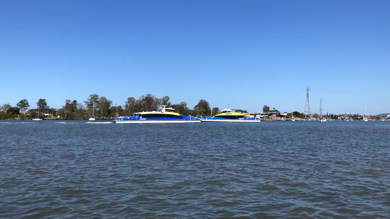 在一个晴朗的日子里，公共交通系统中的两艘双体船在运送通勤者时穿过河流视频下载