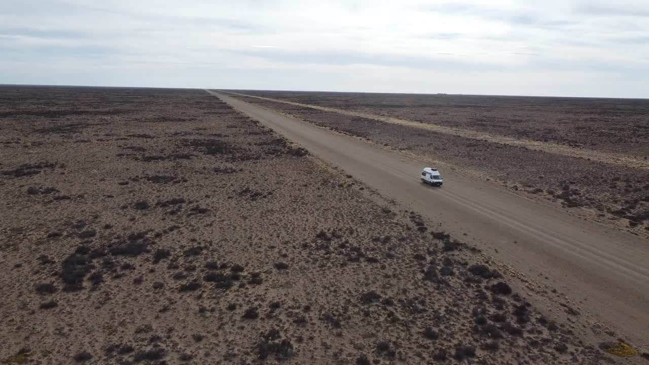 航拍前视图的小白色面包车行驶在砾石路平坦干旱景观视频下载