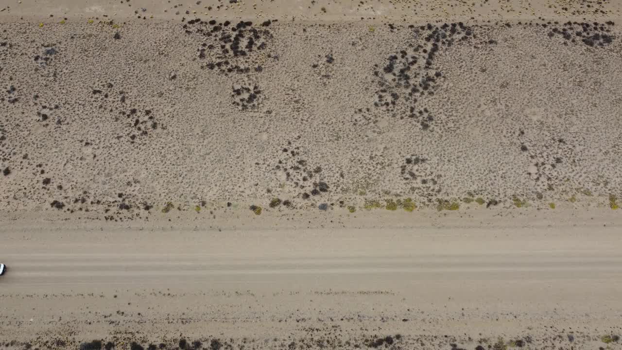 航拍视频，一辆白色小货车在平坦干旱的砾石路上行驶视频下载