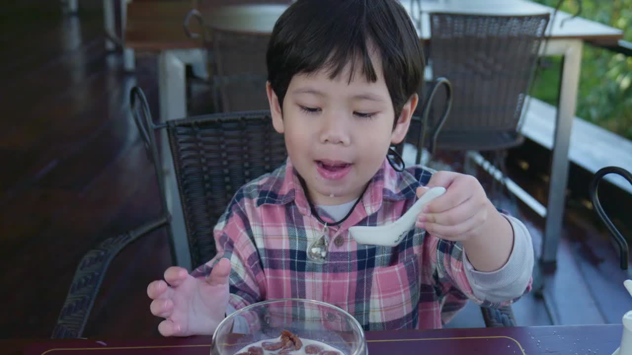 小男孩在度假胜地的餐厅享用早餐。视频下载