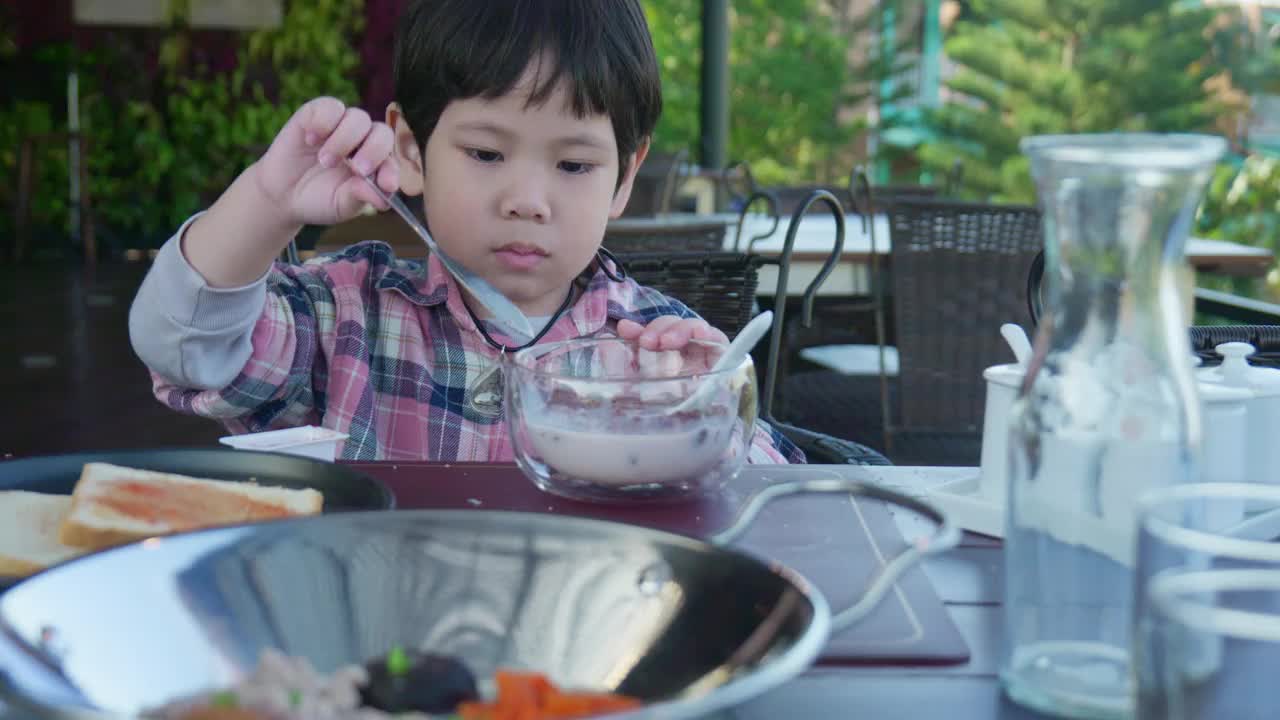 小男孩在度假胜地的餐厅享用早餐。视频下载