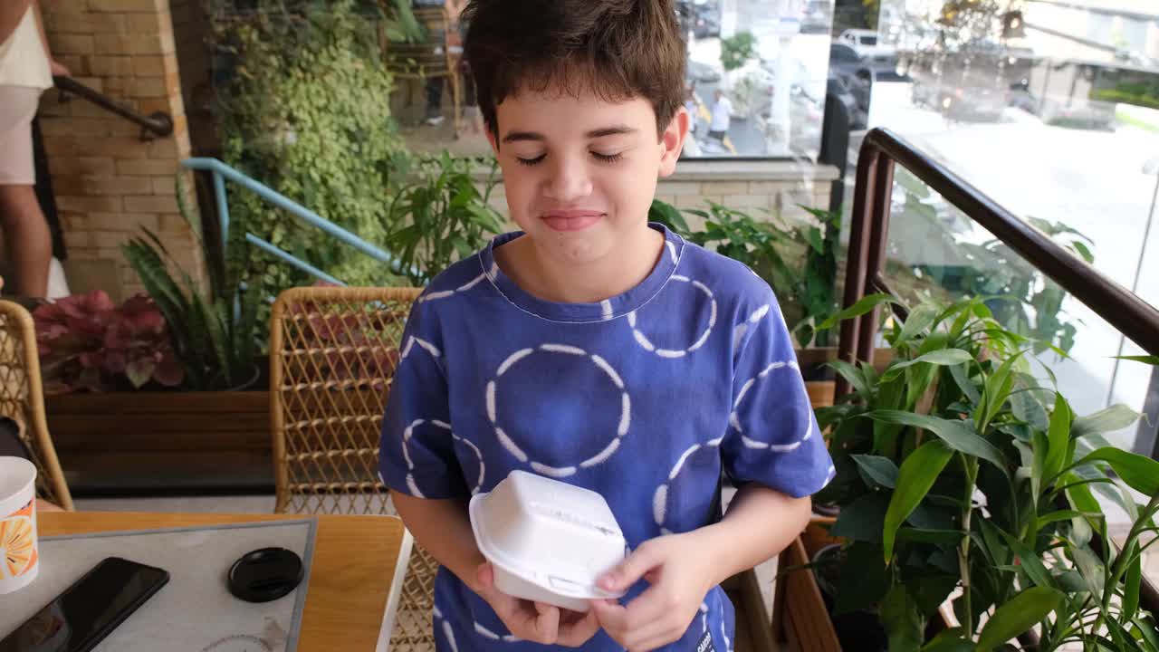 微笑的10岁巴西孩子拿着几个巴西软糖球吃。视频下载