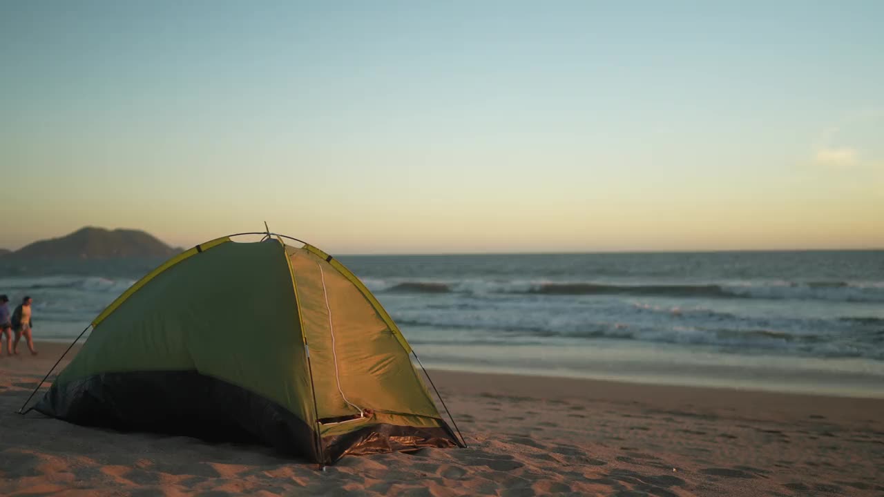 年轻人离开帐篷，在沙滩上伸懒腰视频素材