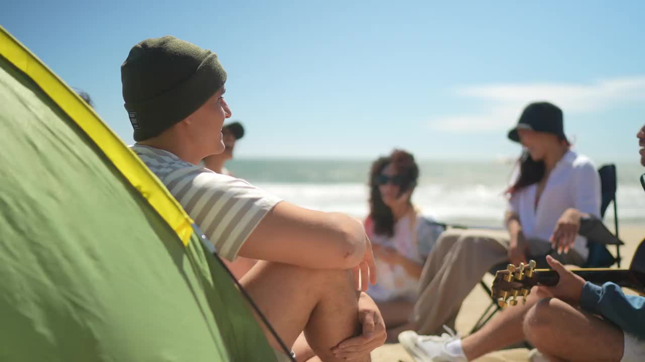 一个中年男子和朋友在海滩上听音乐的肖像视频素材