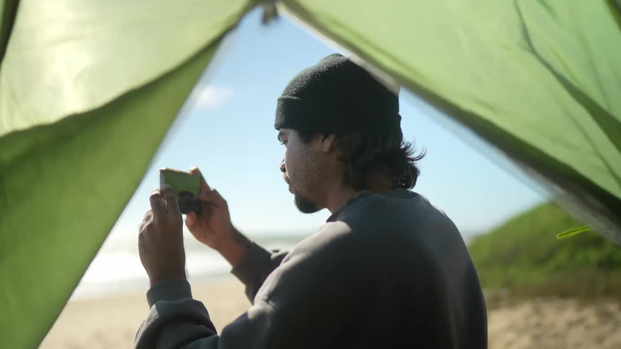年轻人在海滩上用手机拍摄大海视频下载
