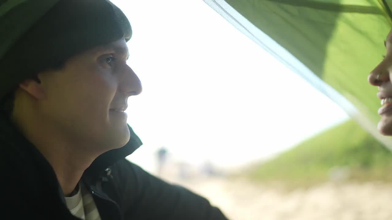 一对夫妇在海滩上的帐篷里聊天的照片视频素材