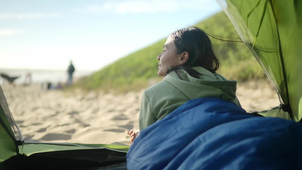 一个年轻女子躺在沙滩上的帐篷里视频下载