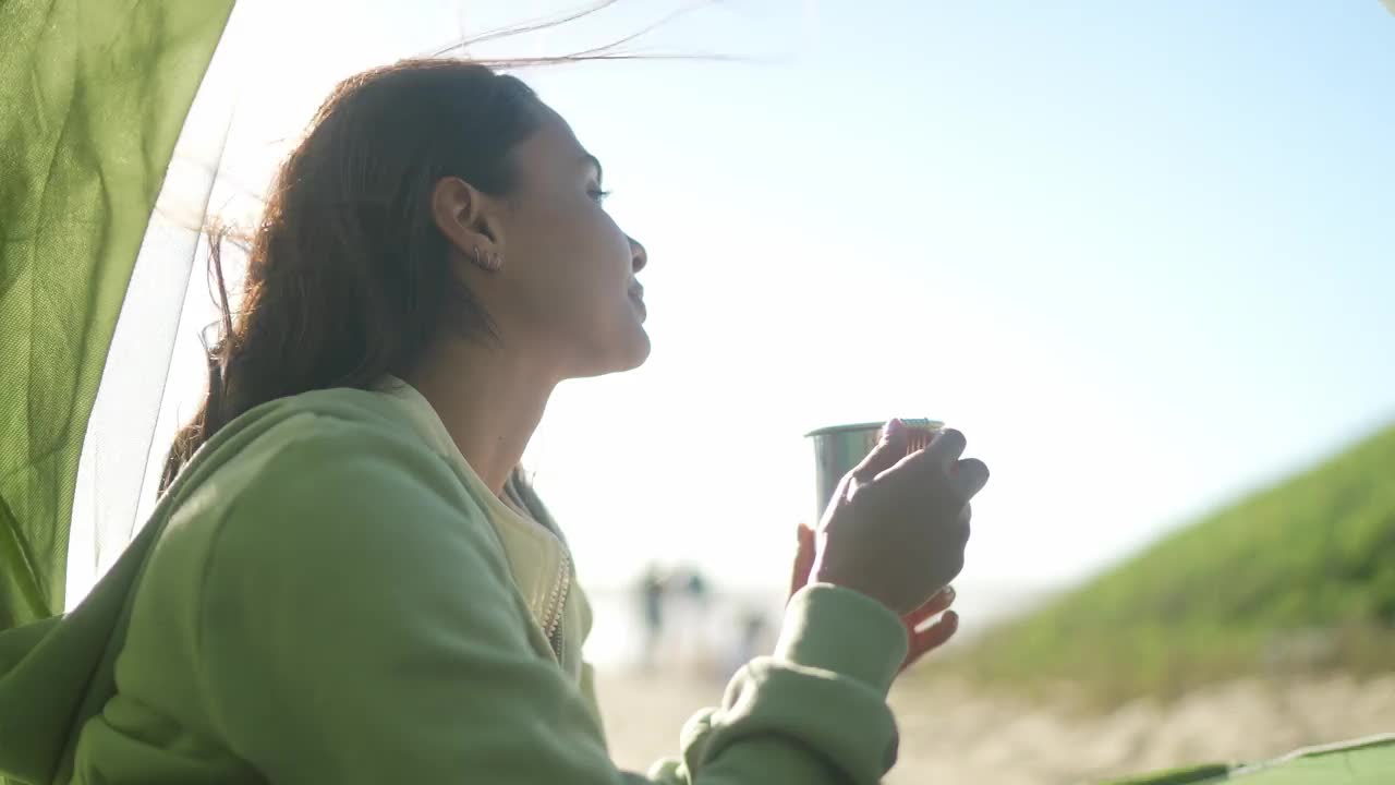 年轻女子一边闻着咖啡，一边在沙滩上欣赏大海视频下载