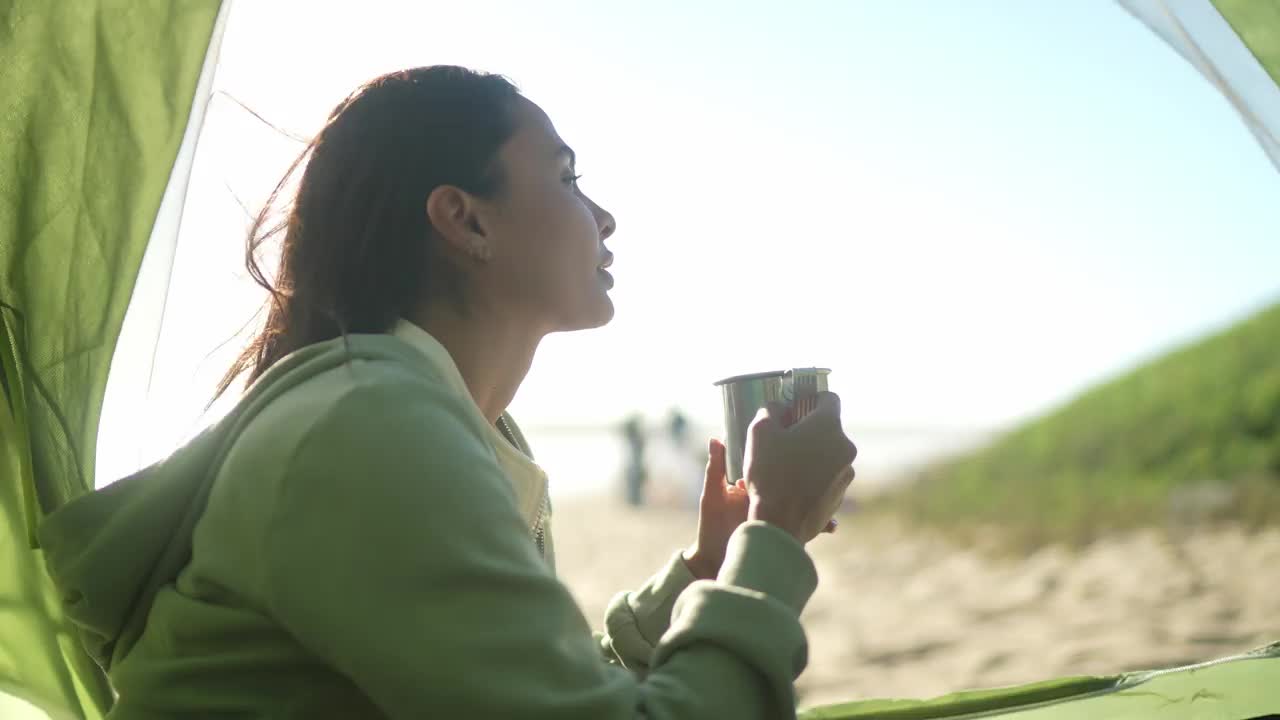 一个年轻女子在海滩上的帐篷里闻着咖啡的味道视频下载