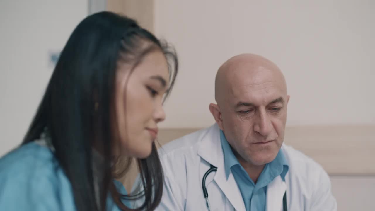 两位医生使用电脑外科医生讨论病人的CT扫描。视频下载