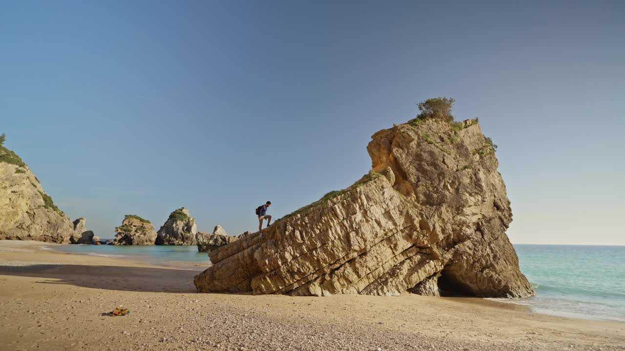 在塞辛布拉，一名男子正在攀爬岩石前往海滩视频下载