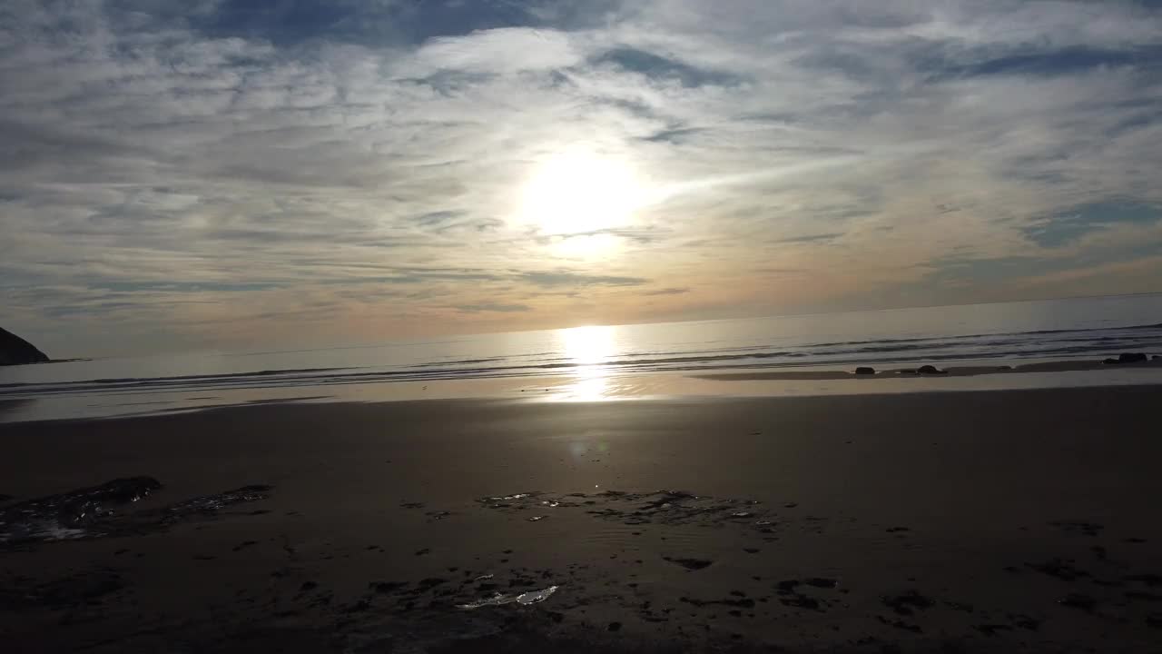 巴塔哥尼亚海岸的日出，相机在面向太阳的沙滩和小波浪上移动得很低视频下载