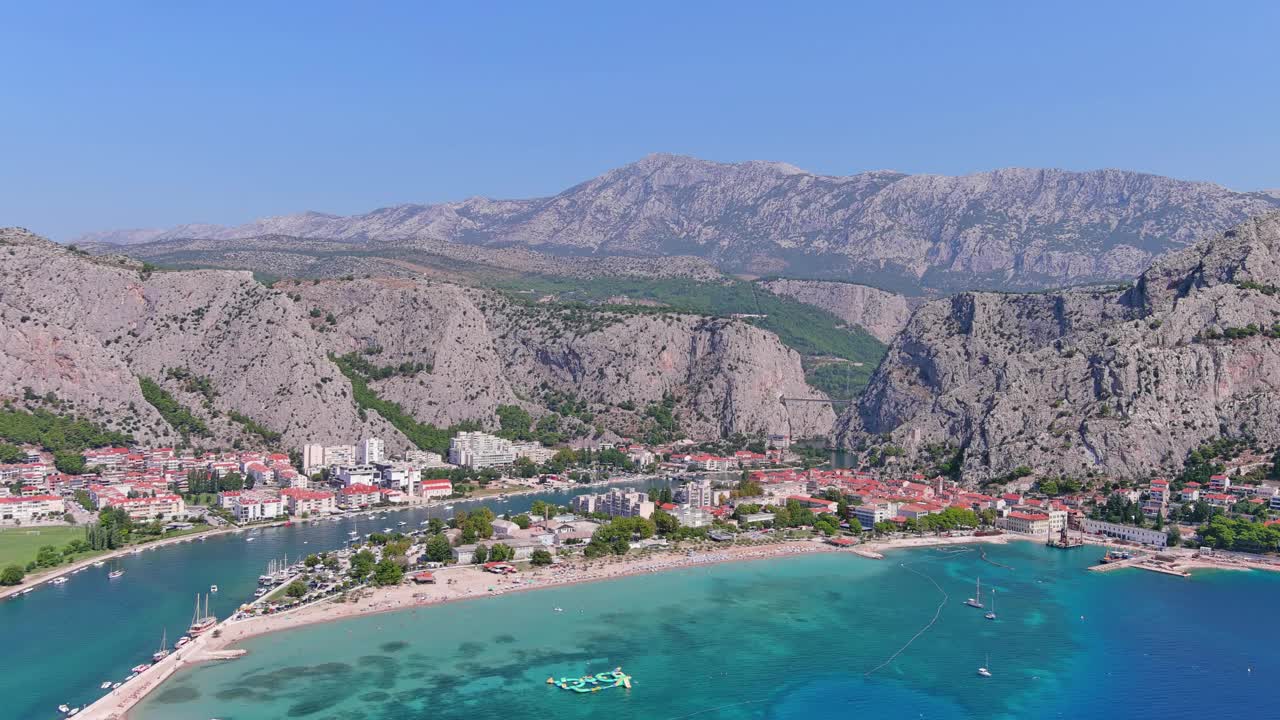 奥米斯，克罗地亚:鸟瞰著名的地中海小镇和亚得里亚海的避暑胜地，蓬塔海滩(Velika plaža)夏日晴朗的蓝天，俯瞰欧洲全景视频下载