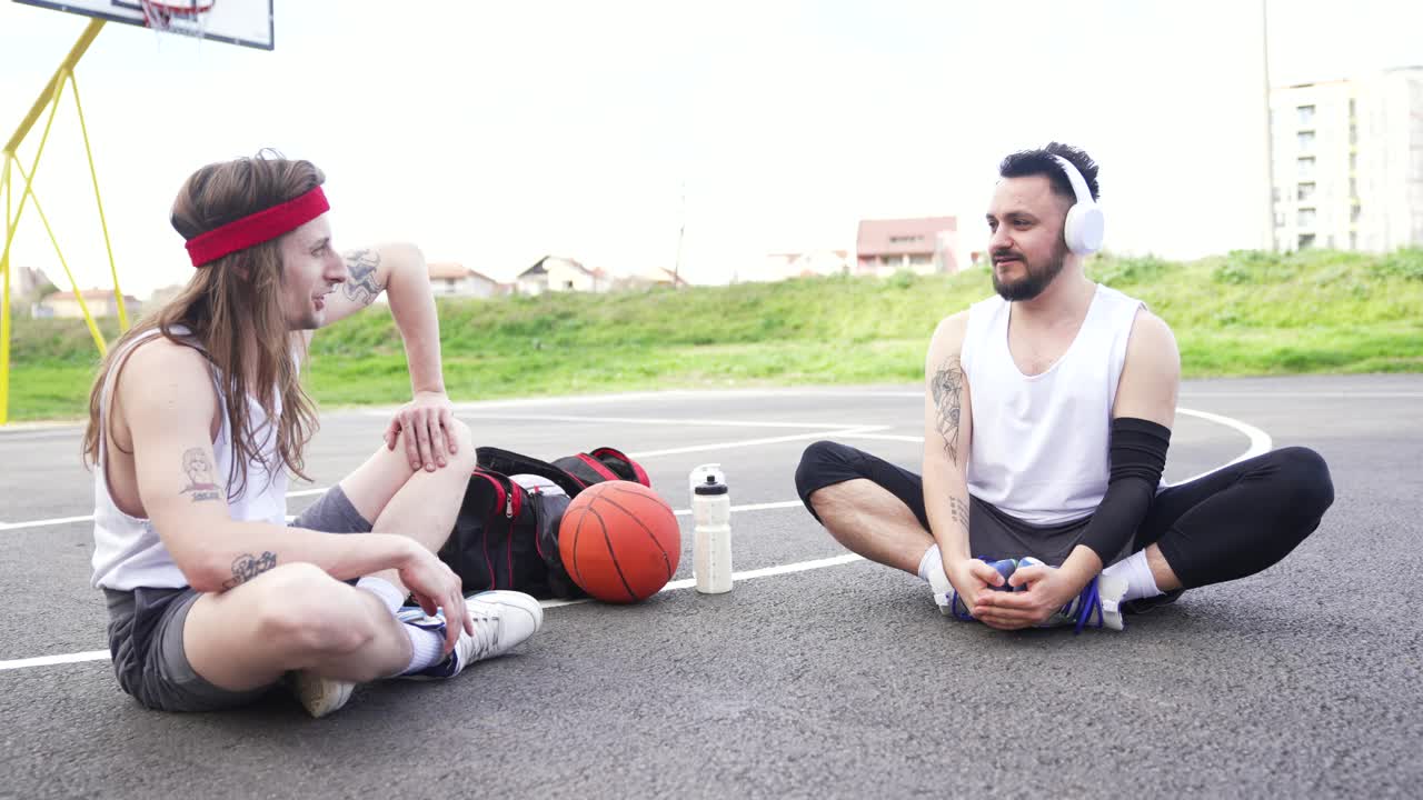 两个朋友坐在篮球场上聊天视频下载