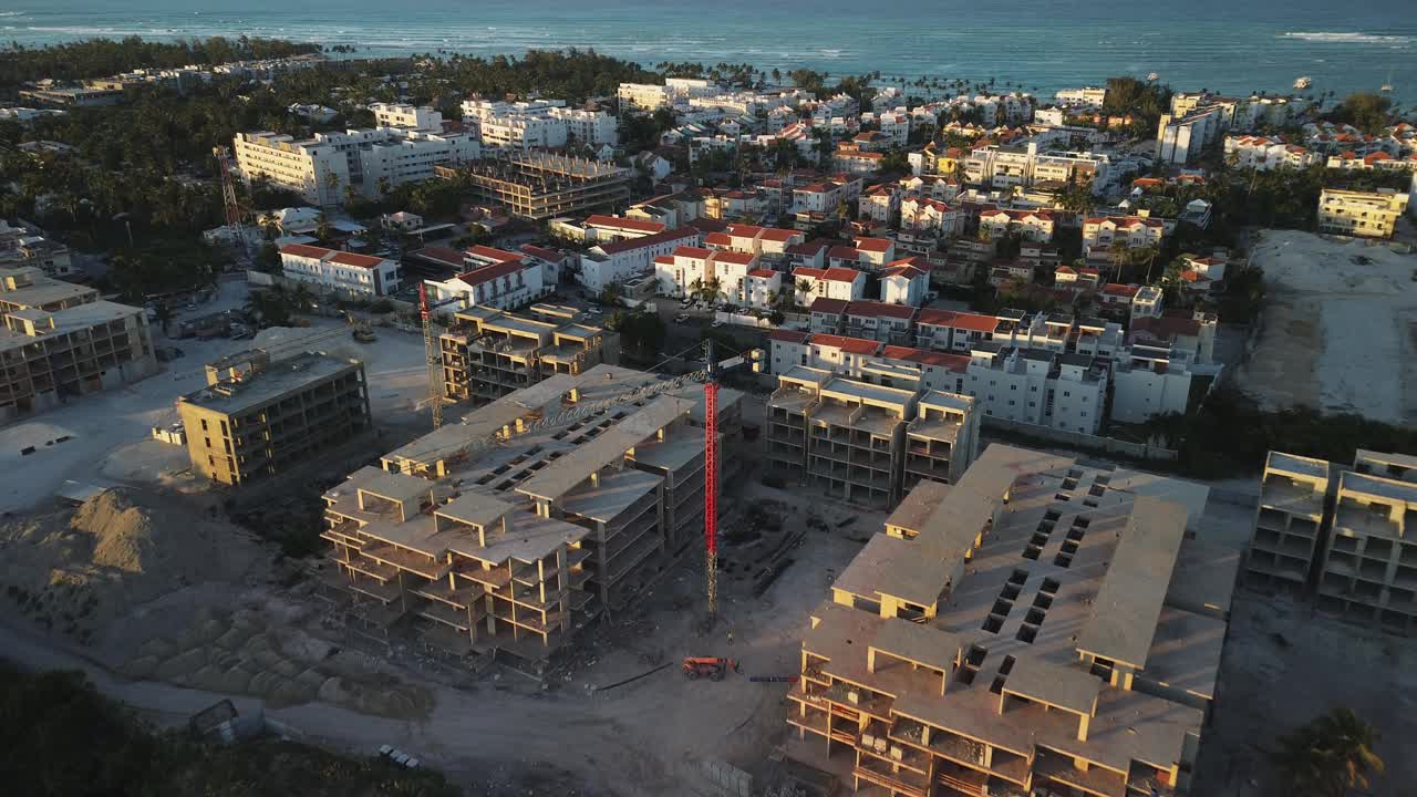 近距离俯视视角重要的建筑工地坐落在繁华的旅游区俯瞰海洋，具有高耸的起重机，所有设置在蓬塔卡纳，多米尼加共和国。放大视频素材