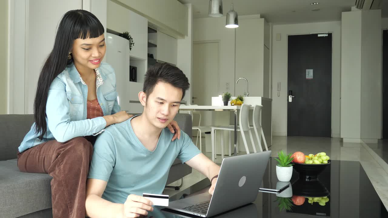 年轻的多种族亚洲夫妇在家里用笔记本电脑处理财务和投资问题视频素材