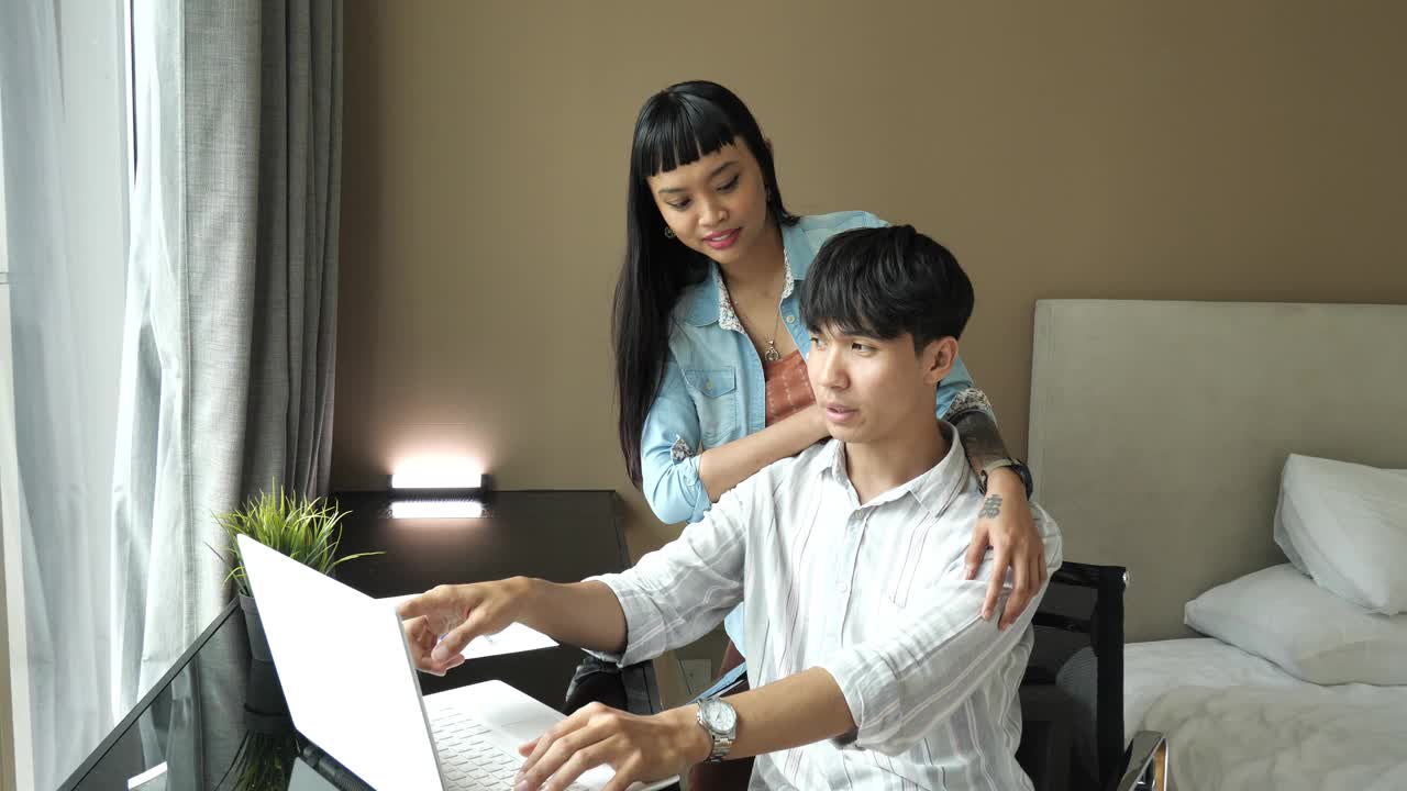 幸福的多种族亚洲夫妇在家里用笔记本电脑工作，处理财务和投资视频下载