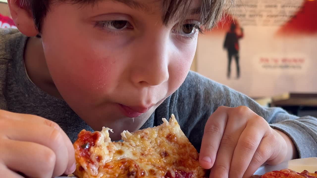 一个小男孩吃芝士披萨的特写视频下载