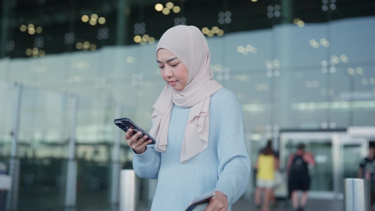 年轻的亚洲妇女戴着头巾，打电话找出租车，从机场回家视频下载