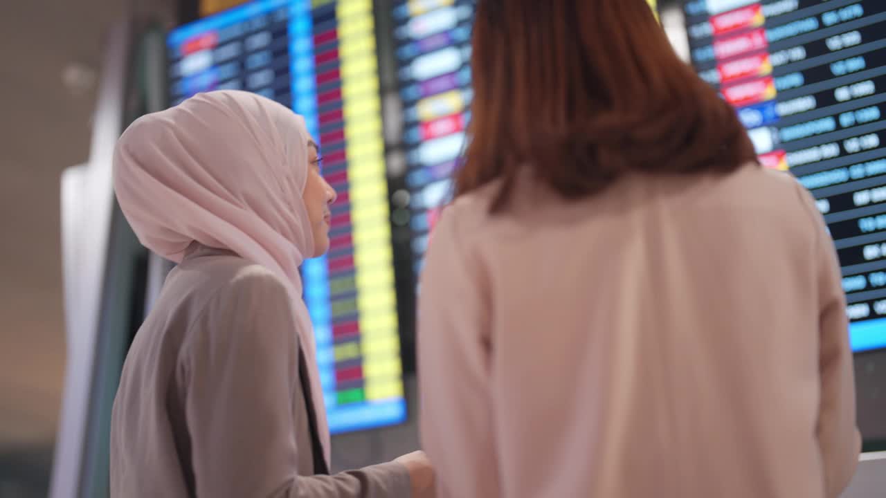 两名年轻的亚洲女子在机场离港处查询航班资料视频下载