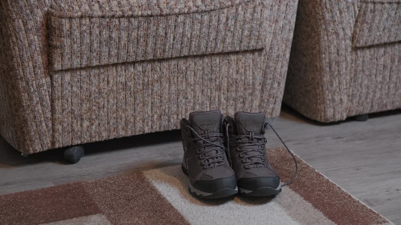 人们在室内系好冬季登山靴的鞋带。一个戴着追踪器的人的特写，他正在做准备视频下载
