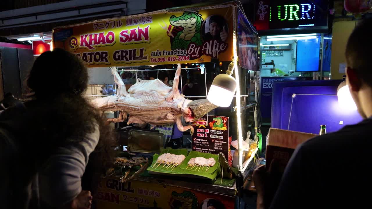 晚上在曼谷的街头小吃，他们在那里烹饪和出售鳄鱼肉。鳄鱼烧烤视频下载