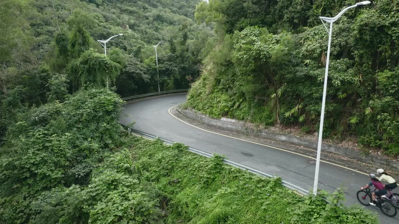 两个年轻的亚洲女子在乡村公路上骑自行车视频下载