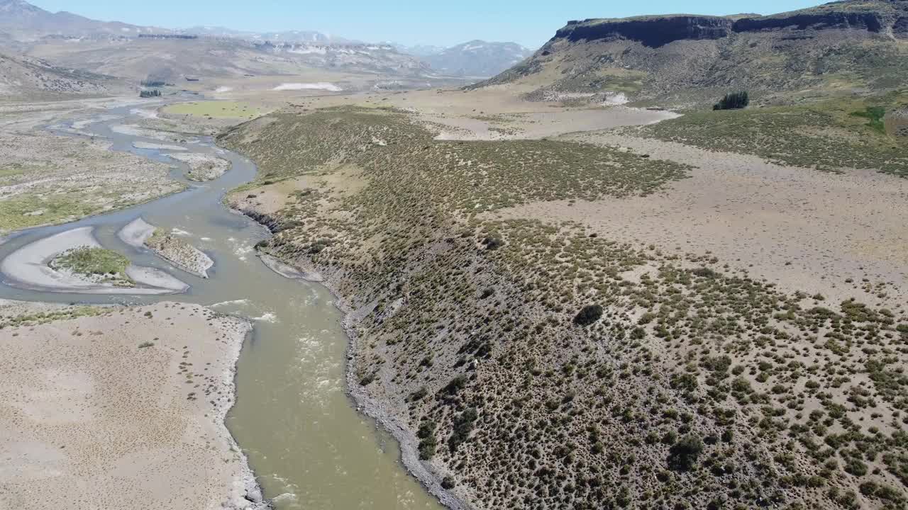 小溪，棕色的水穿过安第斯山脉脚下的干旱景观，远处有山脉。视频下载