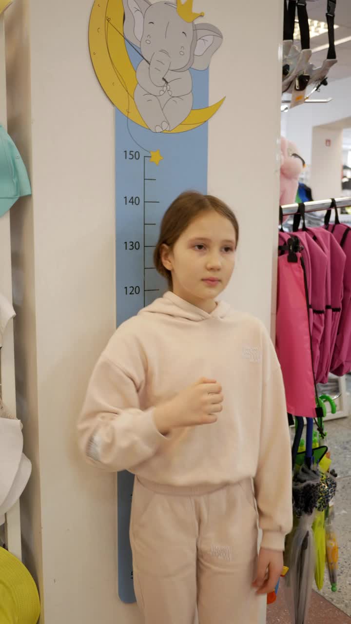措施,增长。少女测量身高，测量还是进步的结果。商店根据孩子的身高选择童装视频下载