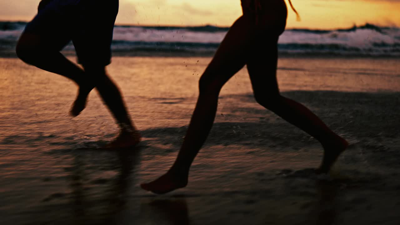 人们，剪影和腿在海滩上的水溅在晚上的乐趣，假期，周末或亲情。朋友们在海边的深夜跑步、玩耍或享受户外自然的特写视频下载