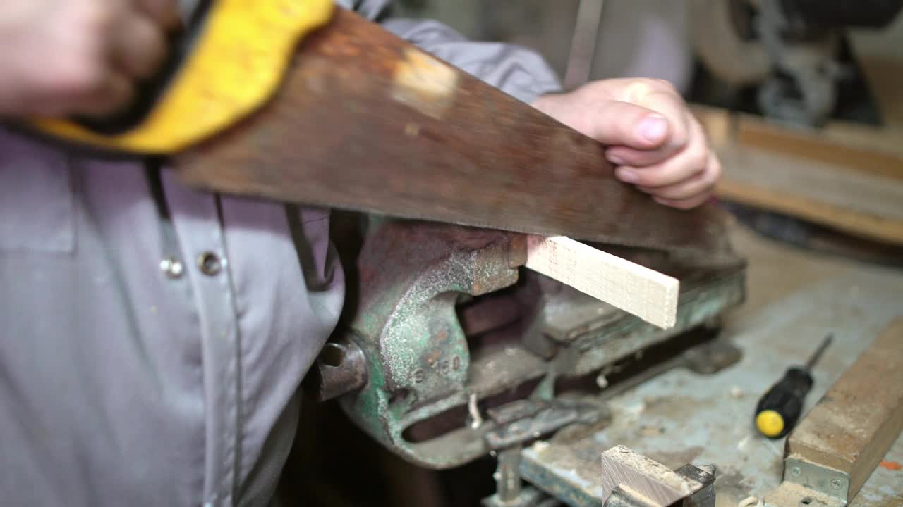 一个成熟的男人在车间里用锯子锯木头视频下载
