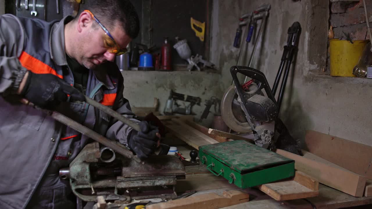 一个成熟的男人在车间里用锯子切割金属视频下载