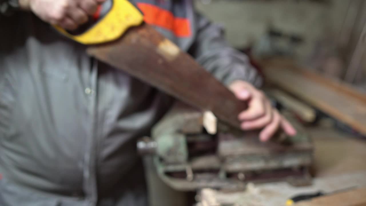 一个成熟的男人在车间里用锯子锯木头视频下载