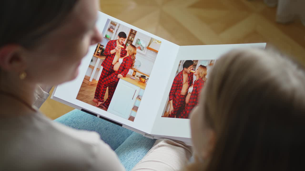 母女俩翻看一本有爸爸和怀孕妈妈照片的书。视频下载