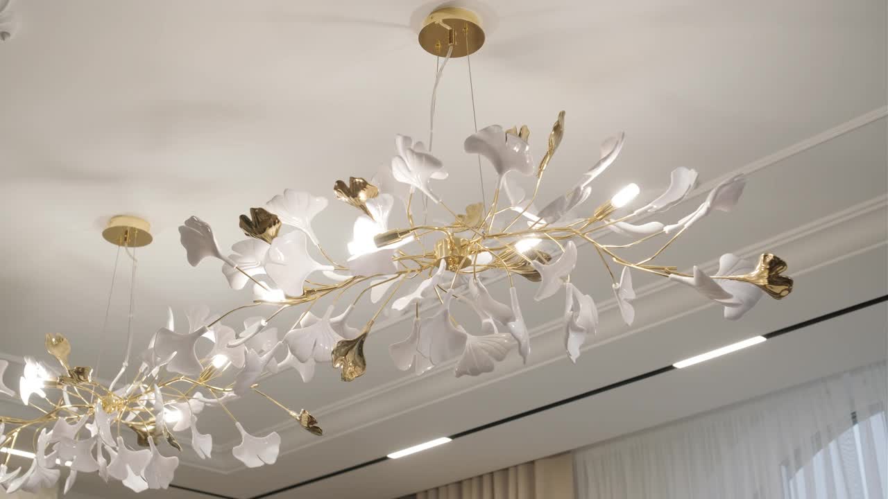 优雅的花吊灯与白色的花瓣和金色的茎照亮了豪华的内部。视频下载