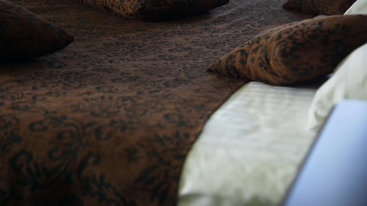 酒店房间里非常漂亮的深色木床。深棕色图案床罩。视频素材