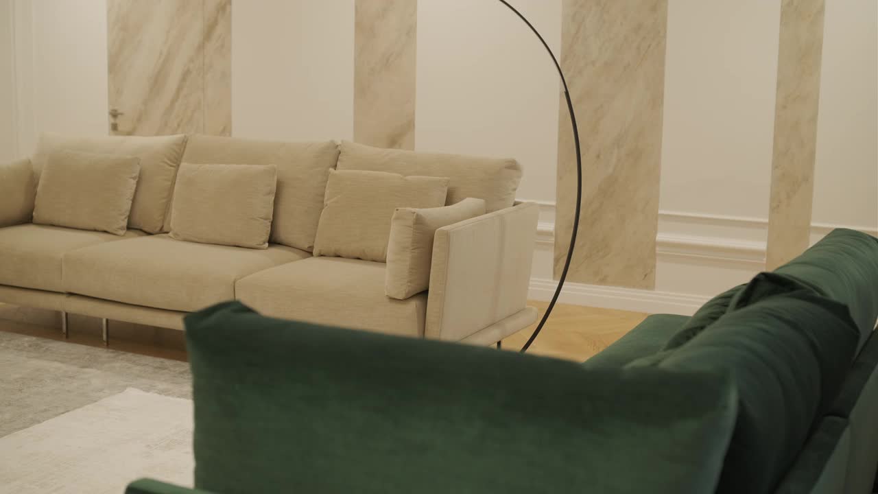 一个舒适的客厅角落，米色沙发，绿色天鹅绒扶手椅，和一个优雅的落地灯视频下载