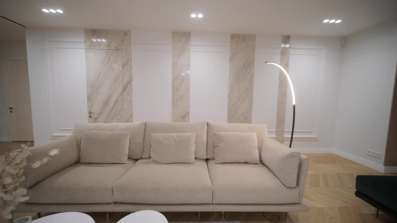 宽敞的客厅设有优雅的沙发，大理石柱，和一个独特的花卉吊灯，沐浴在柔和的光线视频下载