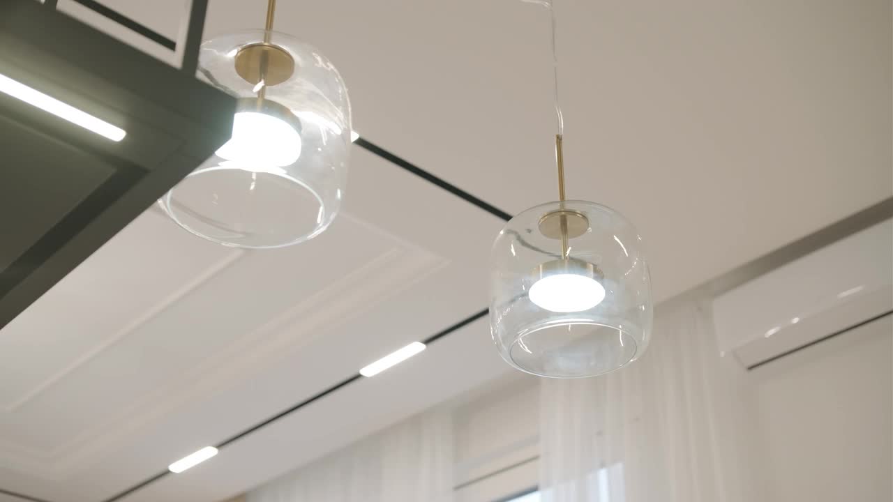 极简主义的金色玻璃吊灯悬挂在带有LED条的现代厨房中视频下载