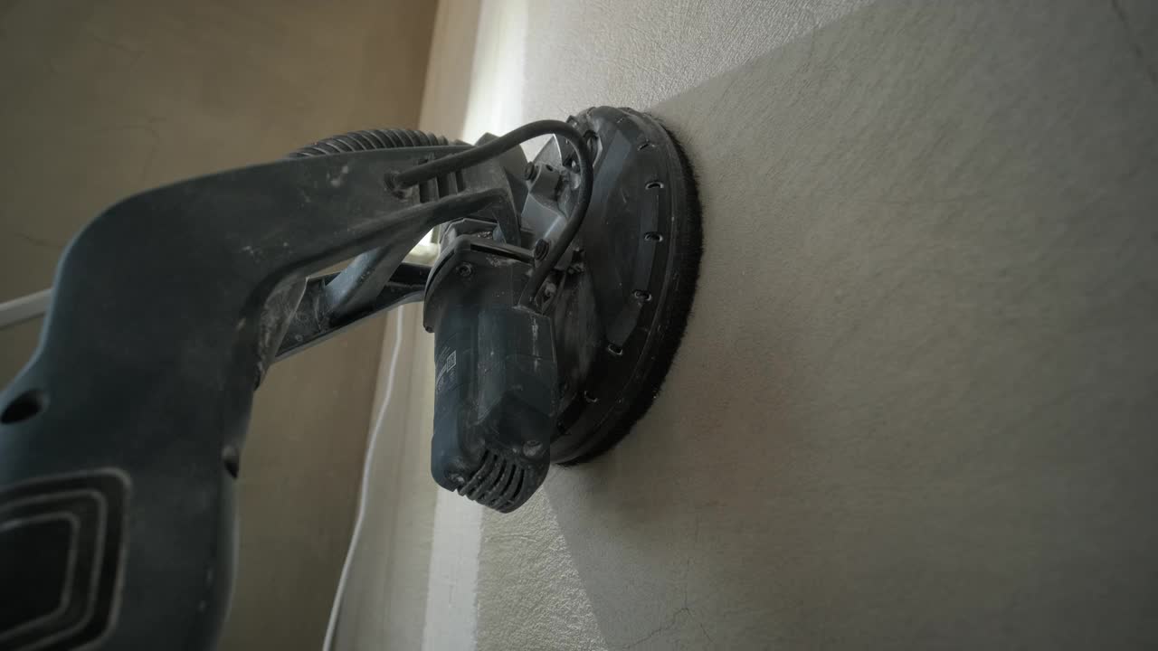 在室内施工的干墙精加工阶段，工人使用磨砂机打磨墙面视频下载