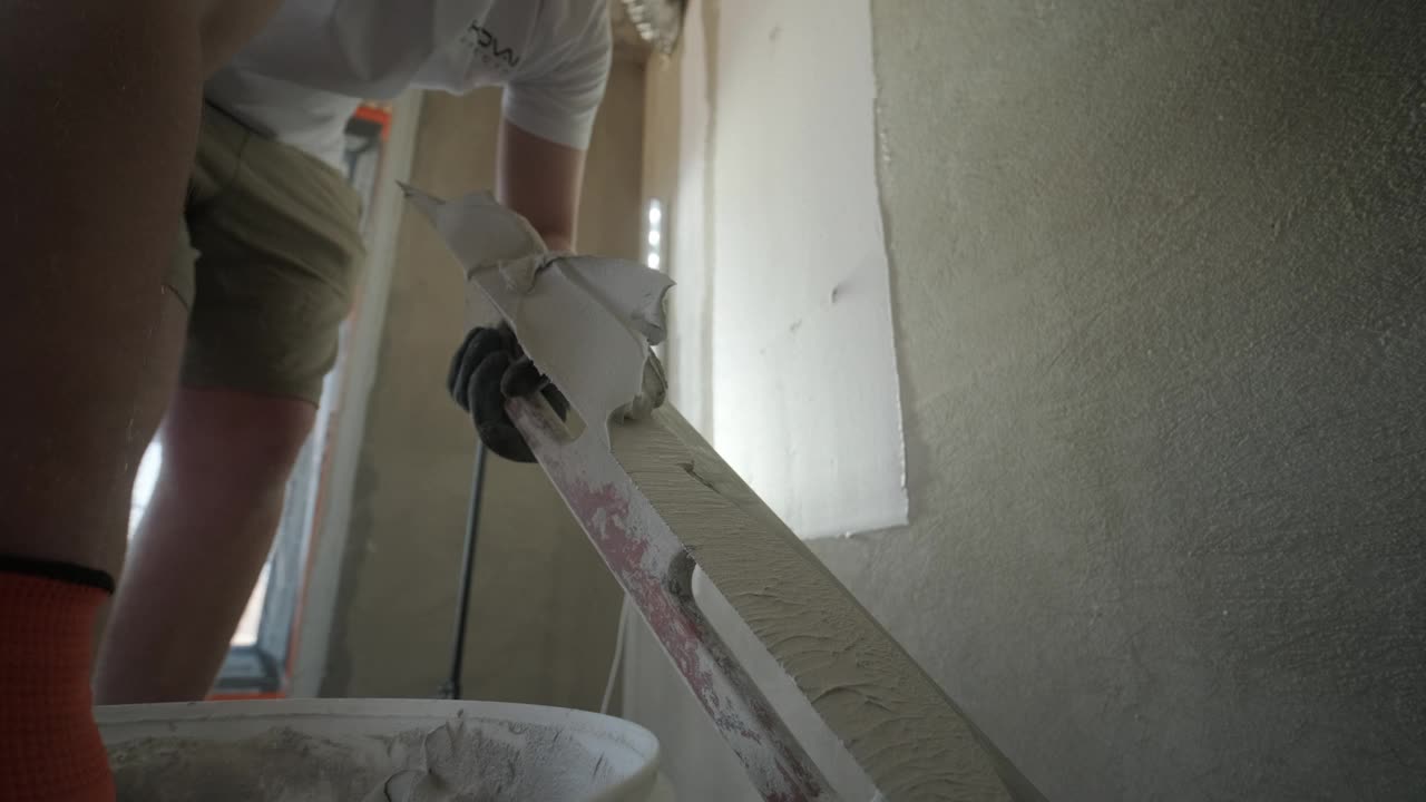 一个工人的手臂在石膏板上安装一个金属角头，以保护和界定灰泥的边缘视频下载