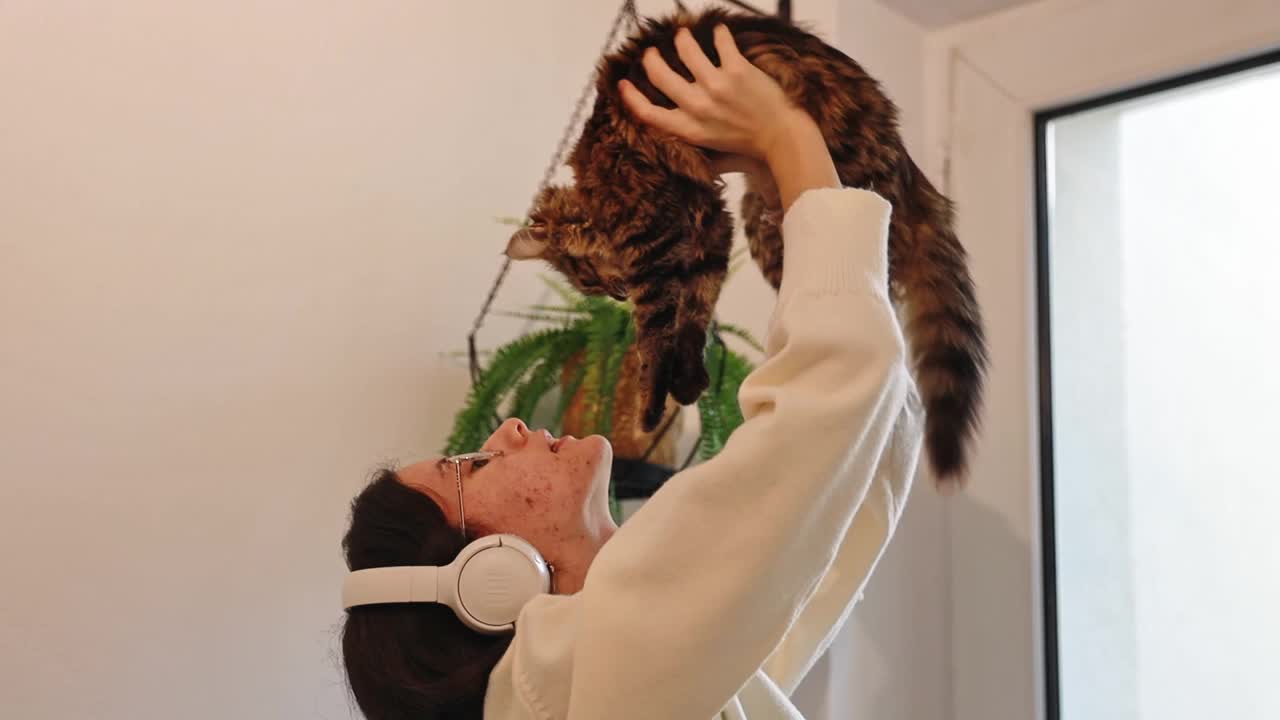 一个十几岁的女孩抱着一只三色小猫，和它玩耍。视频下载