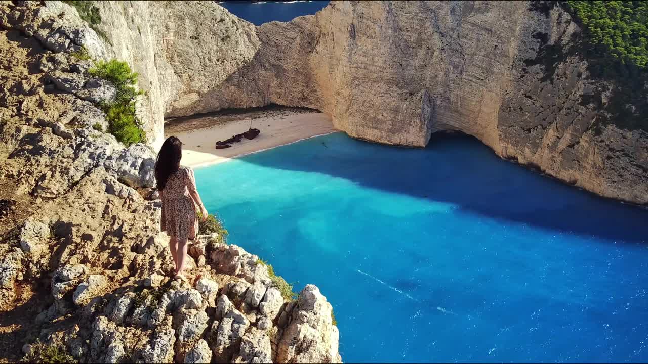 一个女孩在希腊的一座山上看着一艘沉船。视频下载