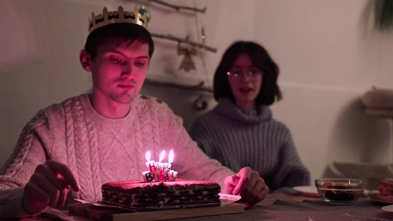 一个年轻人吹灭了蛋糕上的蜡烛。视频下载