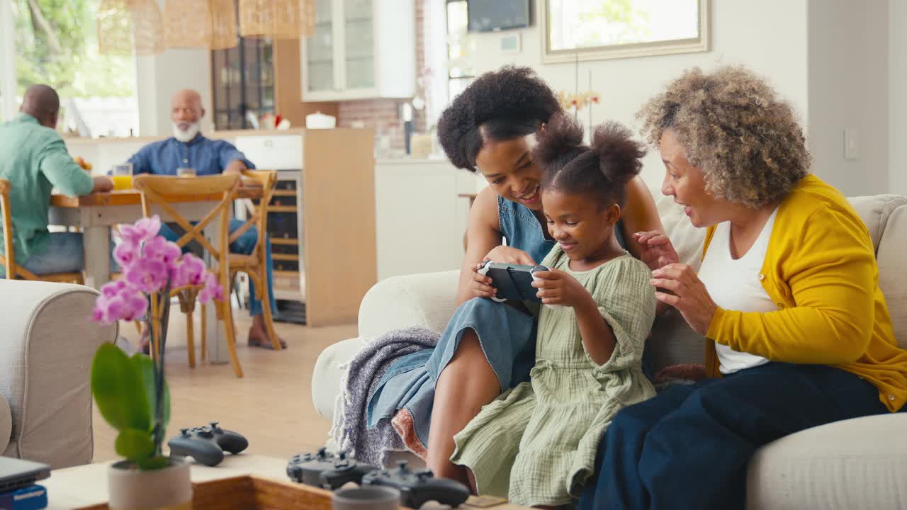 奶奶和妈妈，孙女在家里和家人一起玩掌上游戏机视频下载