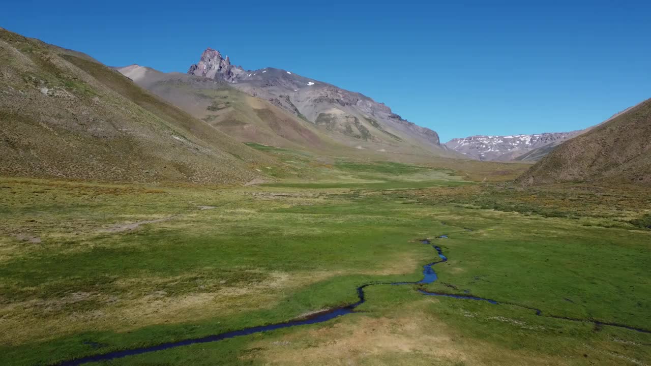 摄像机沿着一条小溪沿着安第斯山脉的绿色山谷而上。视频下载